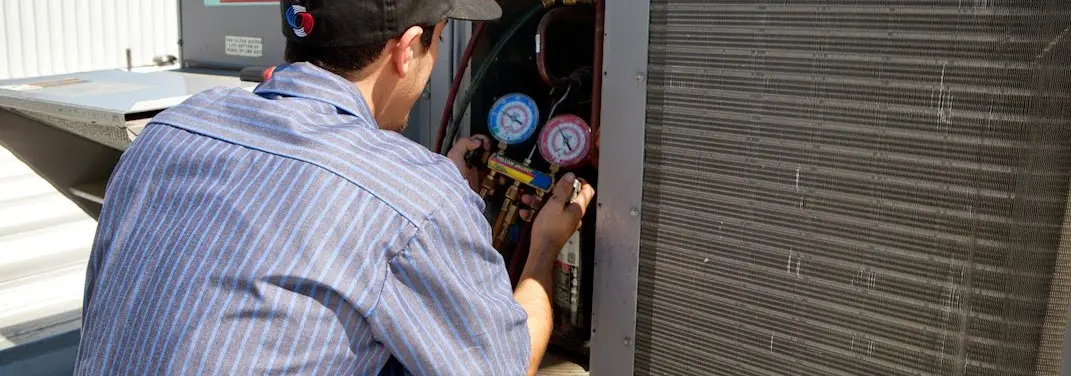 HVAC technician servicing a condenser unit in Edina